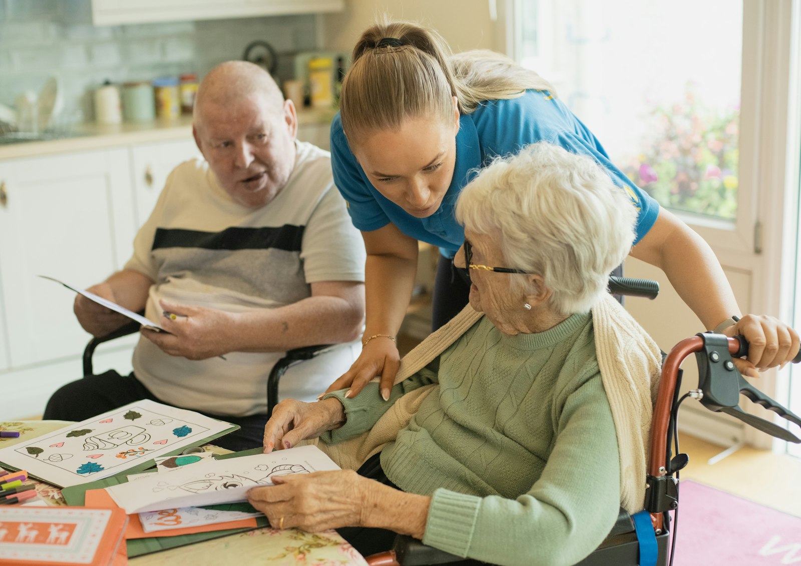 Caregiver guiding two senior residents through a memory care activity