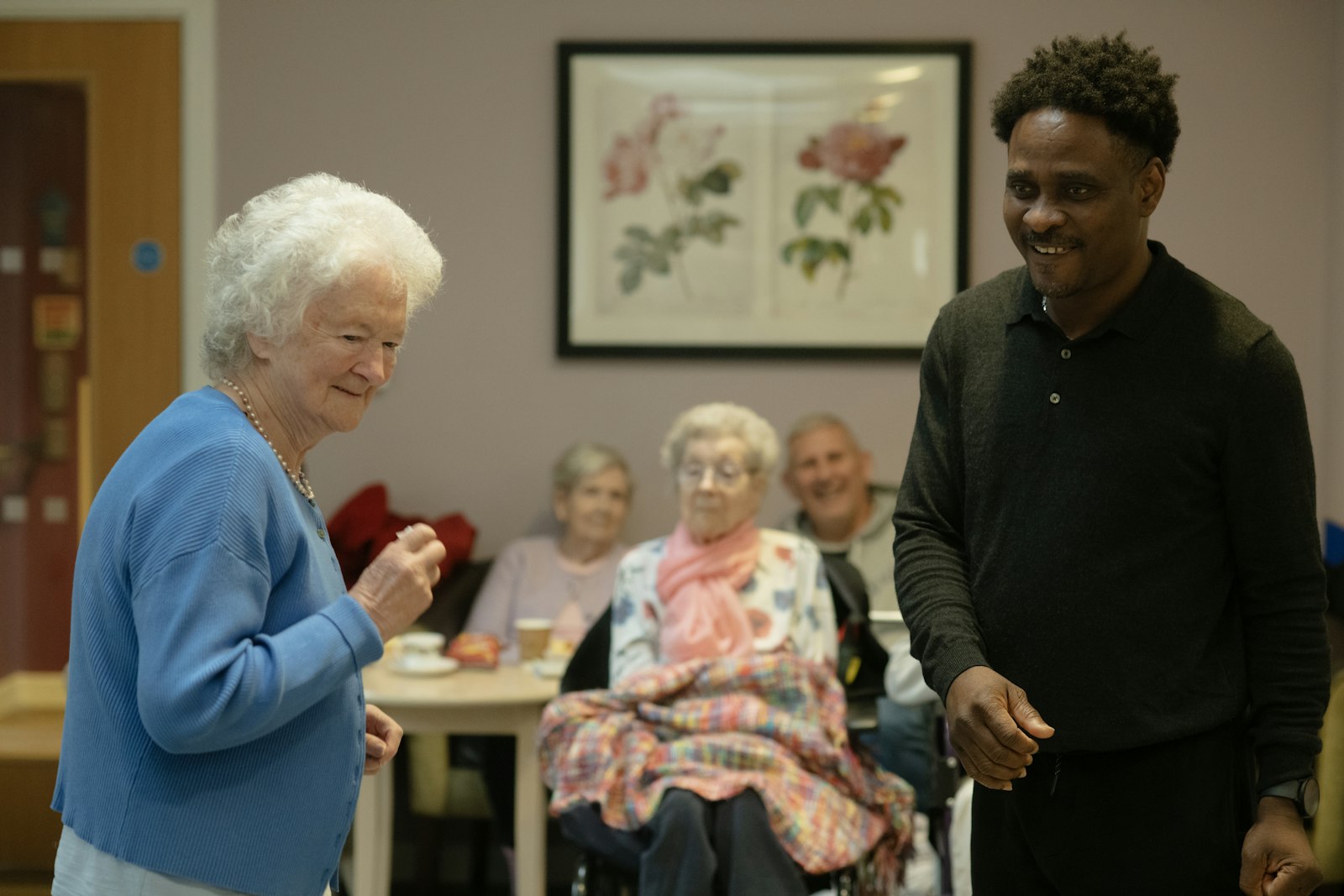 Caregiver and senior residents socializing in a care home common room