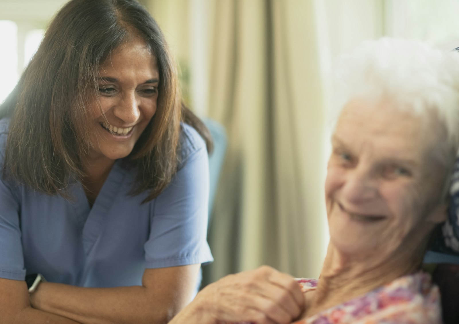 Memory care nurse smiling with an elderly woman in a care home