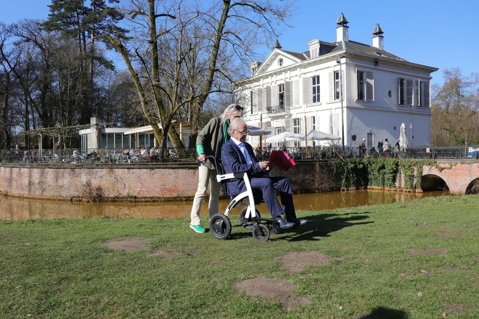 A senior care advisor walking outdoors with an older adult on the grounds of a care home