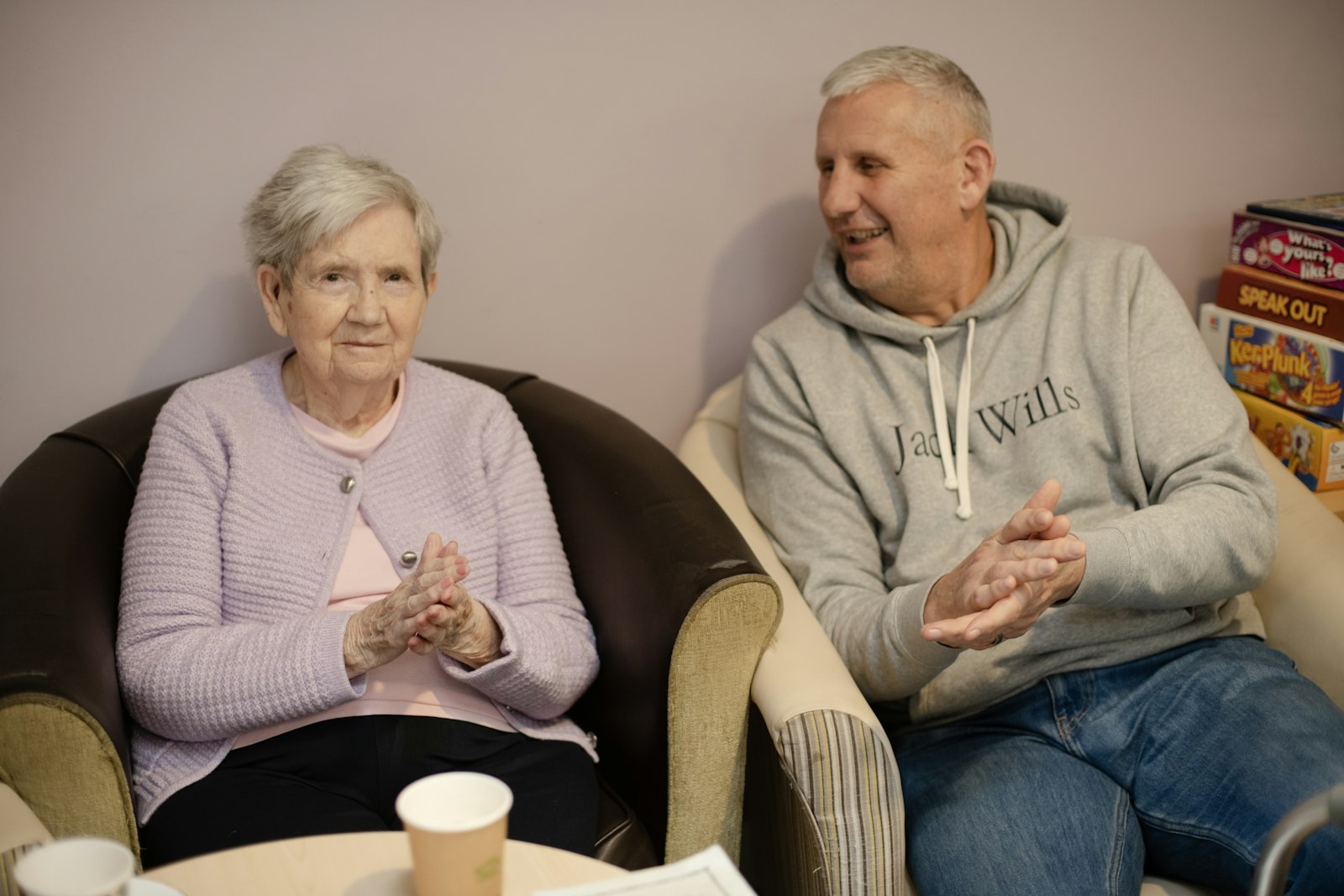 Two senior residents chatting together in a care home common room